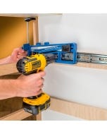 Man using the Rockler Universal Drawer Slide Jig to screw a slide to the wall