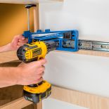 Man using the Rockler Universal Drawer Slide Jig to screw a slide to the wall