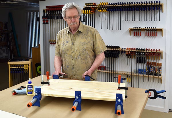 man at workbench clamping a panel