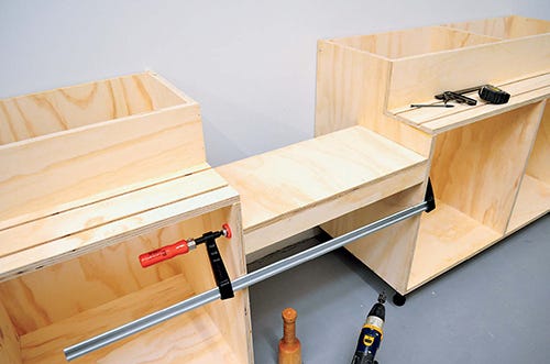 Miter saw station assembly with lowered shelf for saw