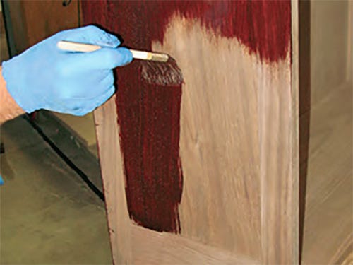 Applying a layer of stain on the side of a bureau