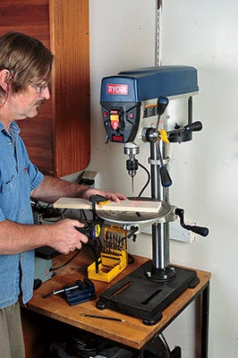 Setting up board on worktable of drill press