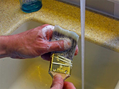 Using soap and water to clean a paint brush