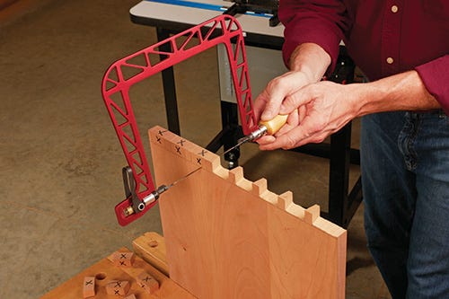 Using a coping saw to cut waste from tail sockets of dovetail joint