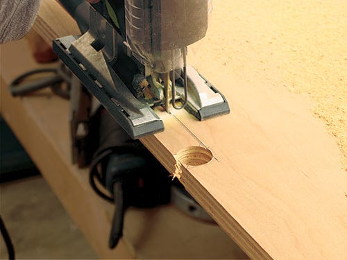 Using a jigsaw to cut holes for wires in media console