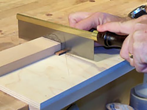 Sawing through small board with gent's saw and a bench hook
