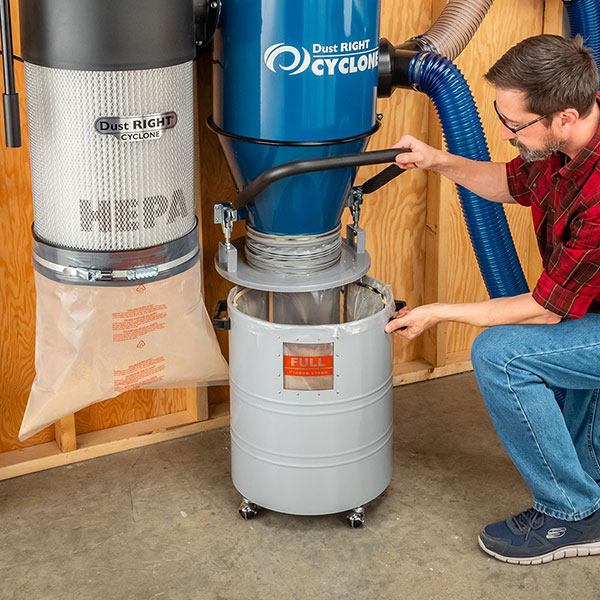 man cleaning chip collection drum on cyclone dust collector 