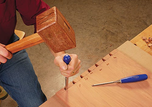 Using large mallet and chisel to clean dovetail tailboard