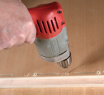 Drilling pilot holes for installation screws next to biscuit slots