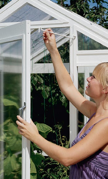 Placing metal hook in greenhouse to hold door open when in use