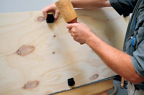Pounding plastic leveling feet into bottom of miter station carcass