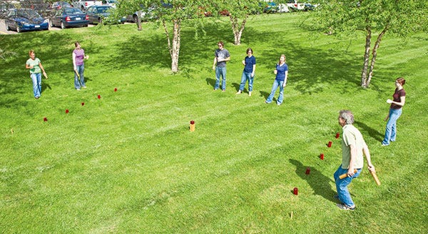 people playing a Kubb game in a grass yard