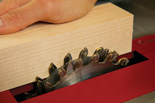 A board marked for a tenon cut next to a stacked dado set in a table saw