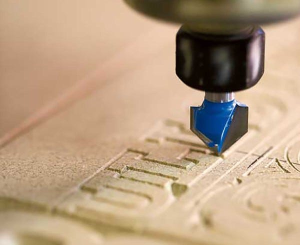 Close-up of a router bit installed in a cnc machine making decorative letter carvings