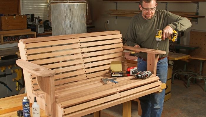 man using drill on wooden porch swing