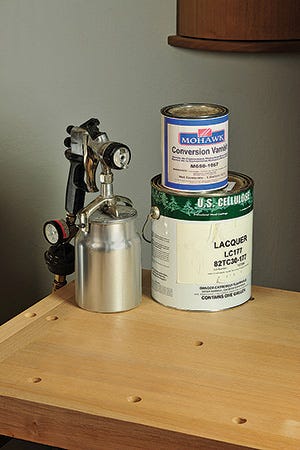 Cans of varnish and matte finish along with a spray gun