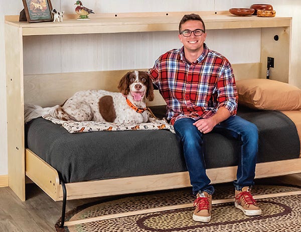man and dog sitting on a Murphy bed