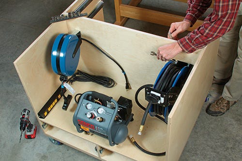Extension cord reel, air compressor and hose kit in outfeed table storage