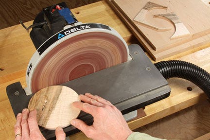 Using disc sander to smooth edges of a circular inlay