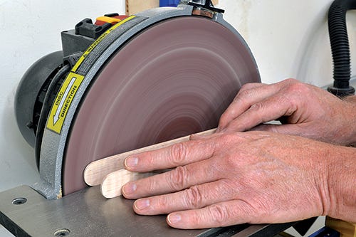 Using sander to smooth out sides of tongs