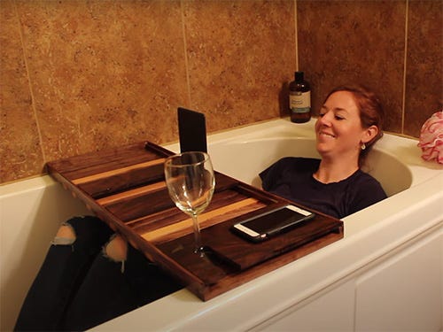 Slatted walnut bath tray sitting over bathtub