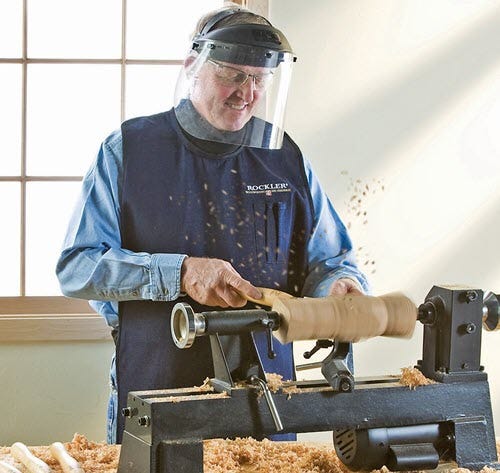 man turning wood wearing face shield