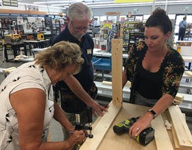 two women measuring wood pieces